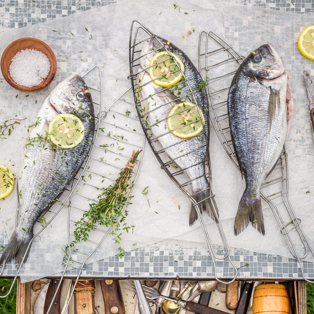 Seasoning freshly caught sea bream with salt and lemon for grilling
